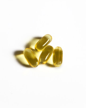 Four yellow capsules sit on a white surface.
