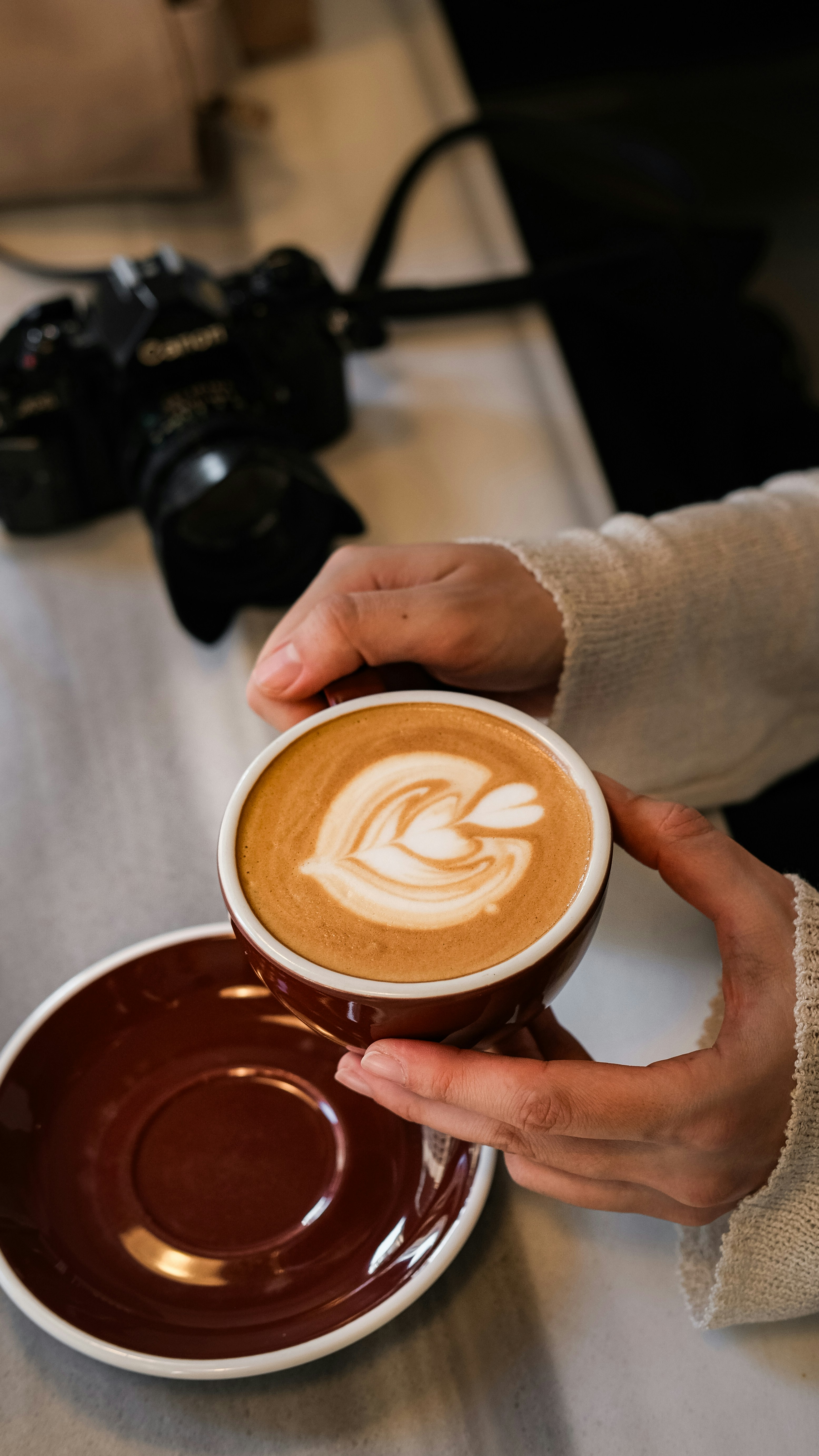 A finished cappuccino in a ceramic cup on a home kitchen counter, with visible layers of espresso and steamed milk