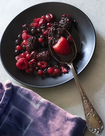 Mixed berries are served on a black plate.