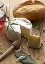 Cheese, bread, and honey on a wooden board.