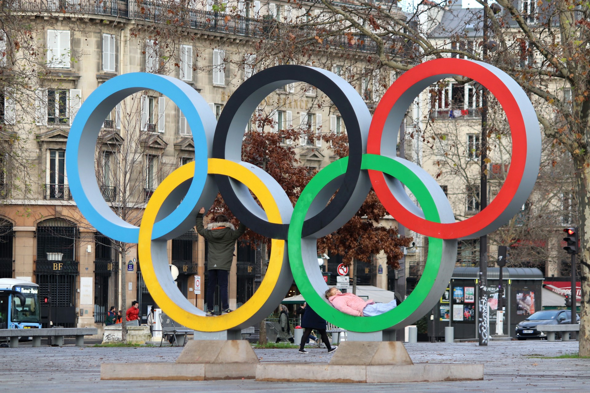 The olympic rings stand in a city square.