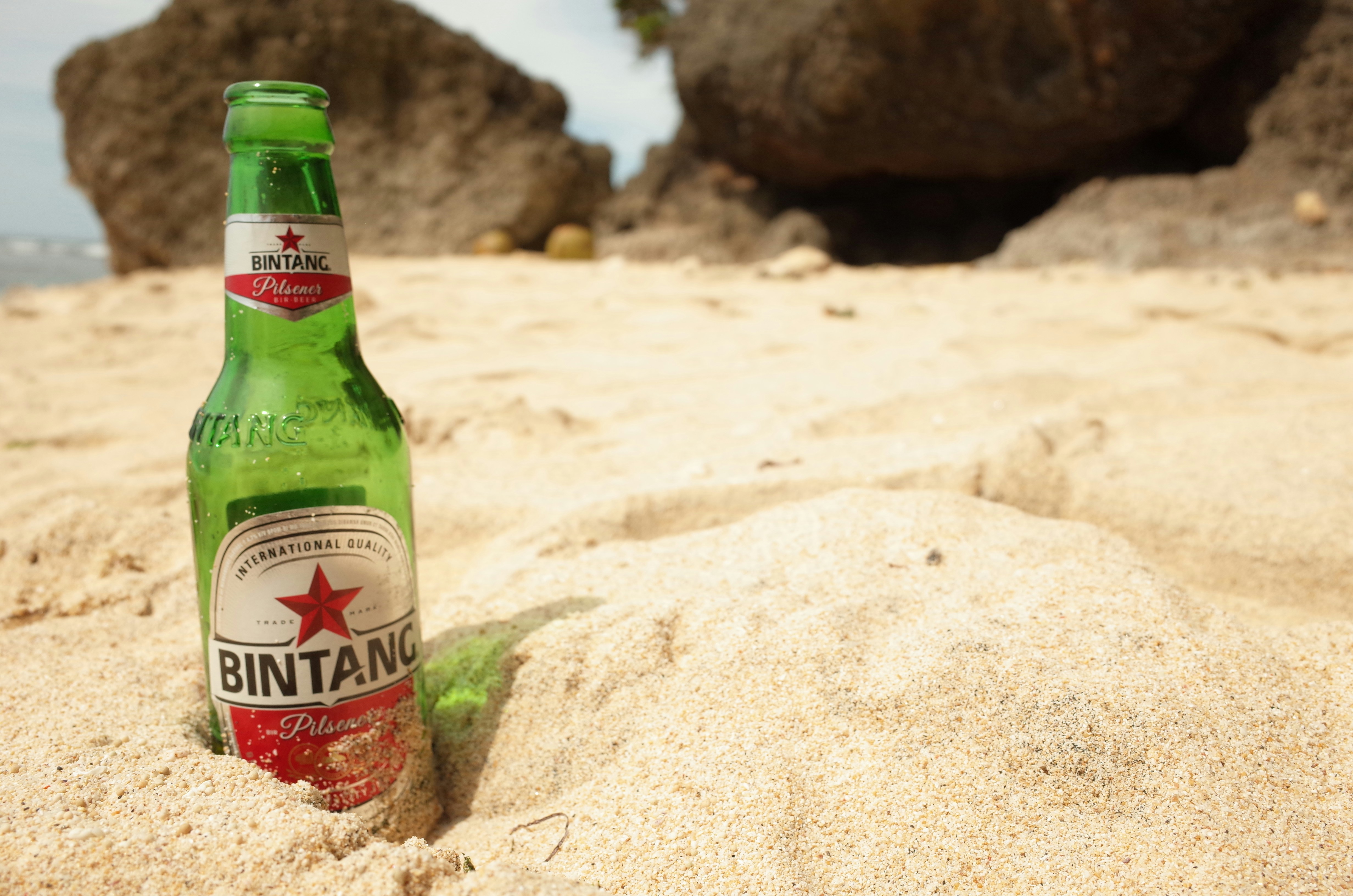 Botol bir Bintang di pantai berpasir.