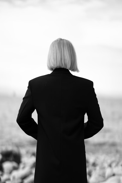 Woman with blonde bob facing an ocean.