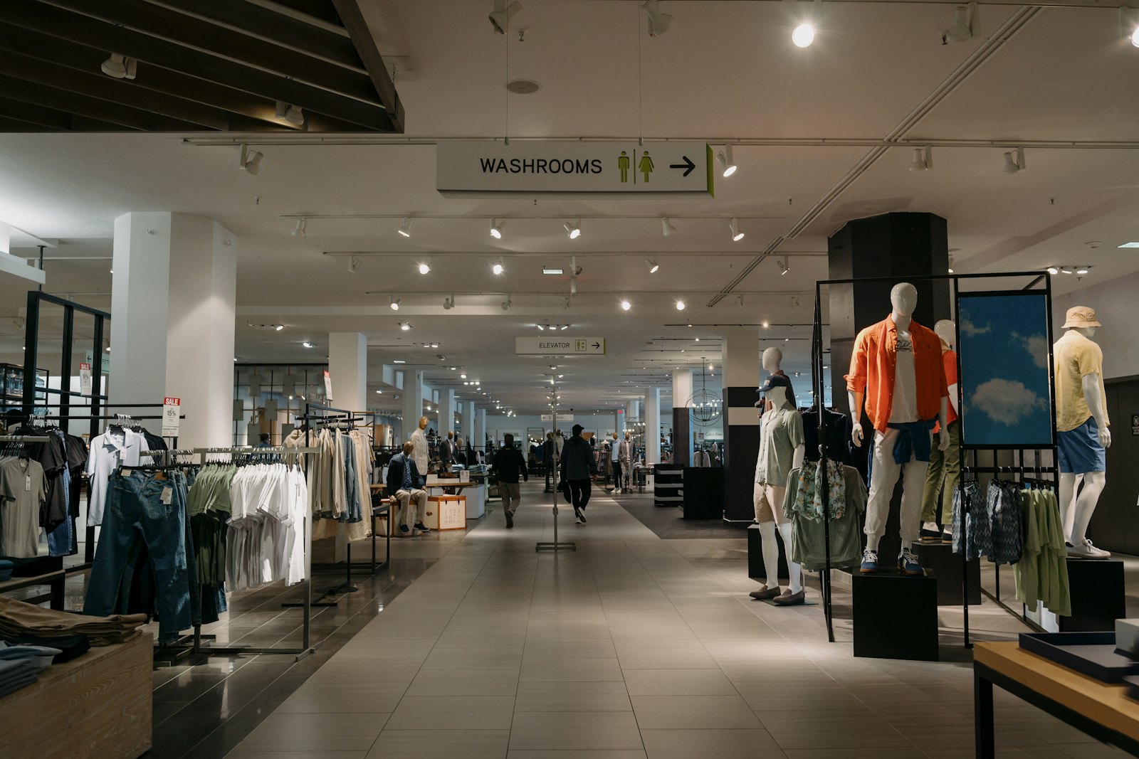 A department store floor with mannequins and racks of clothing under bright ceiling lights