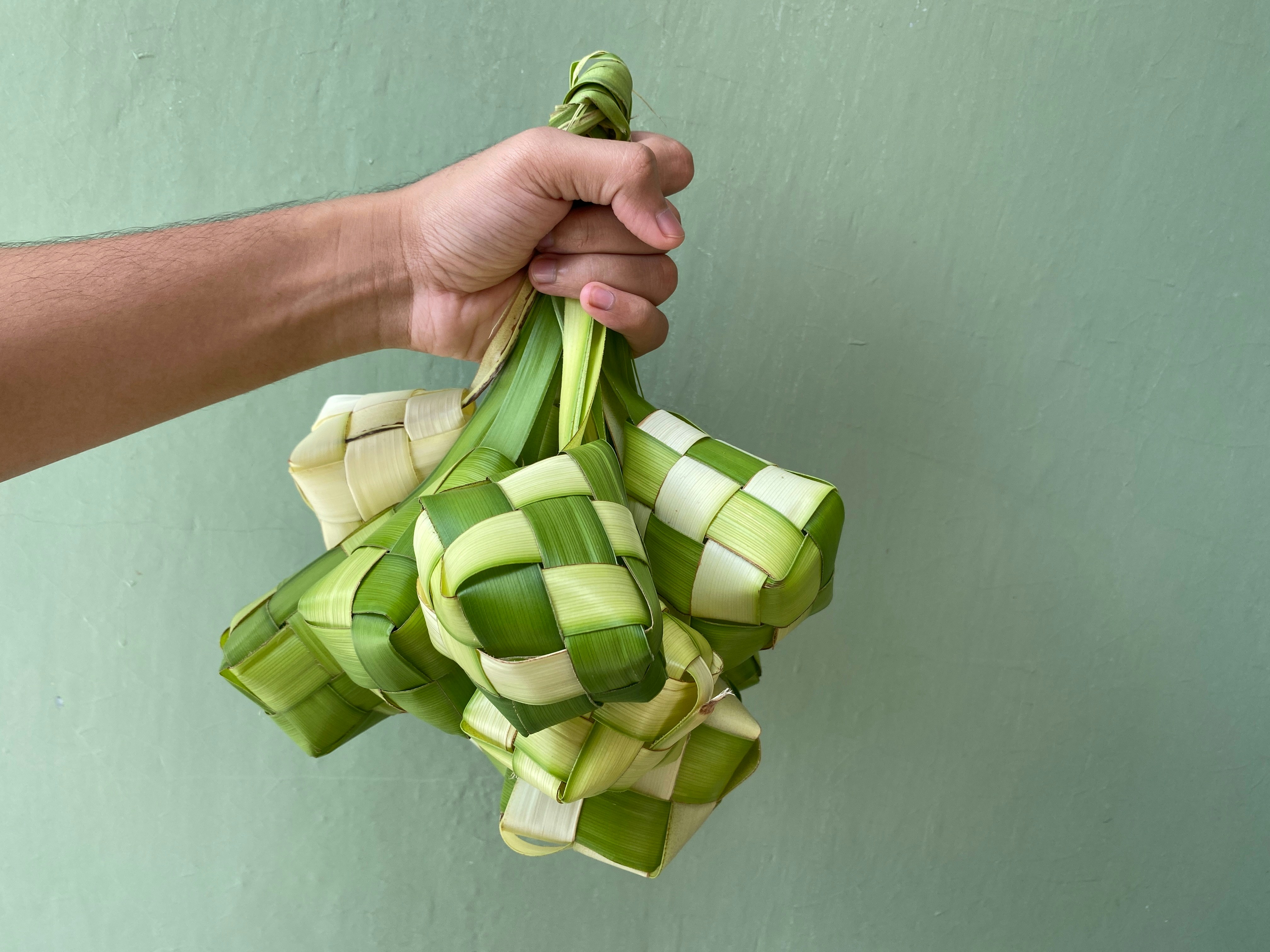 Hand holding a bunch of ketupat.