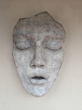 Stone mask of a face with closed eyes.