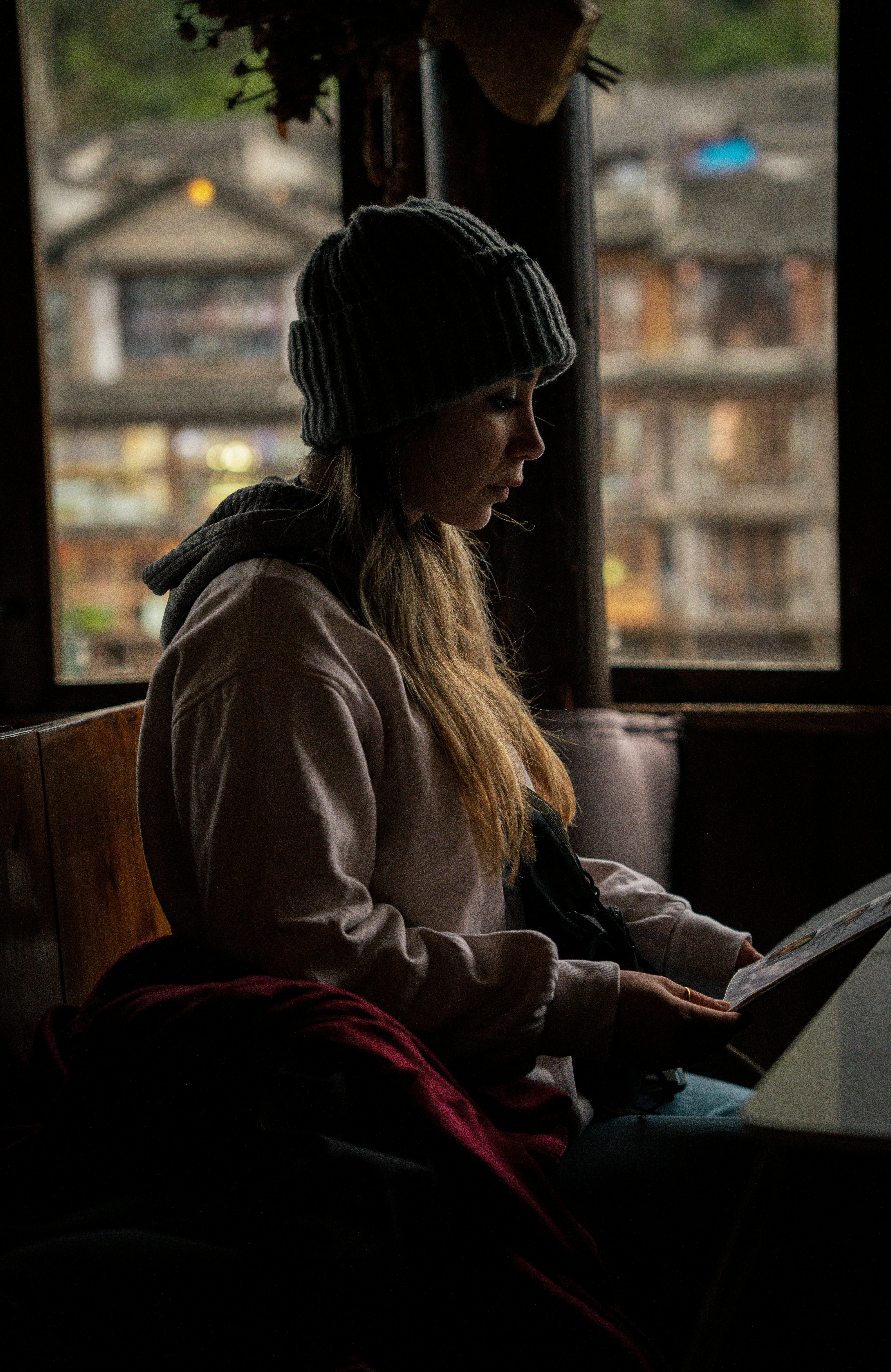 La mujer está leyendo junto a la ventana.