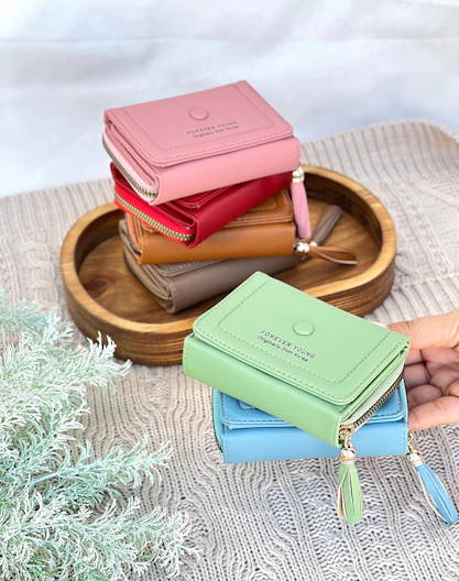 Colorful wallets stacked on a wooden tray.