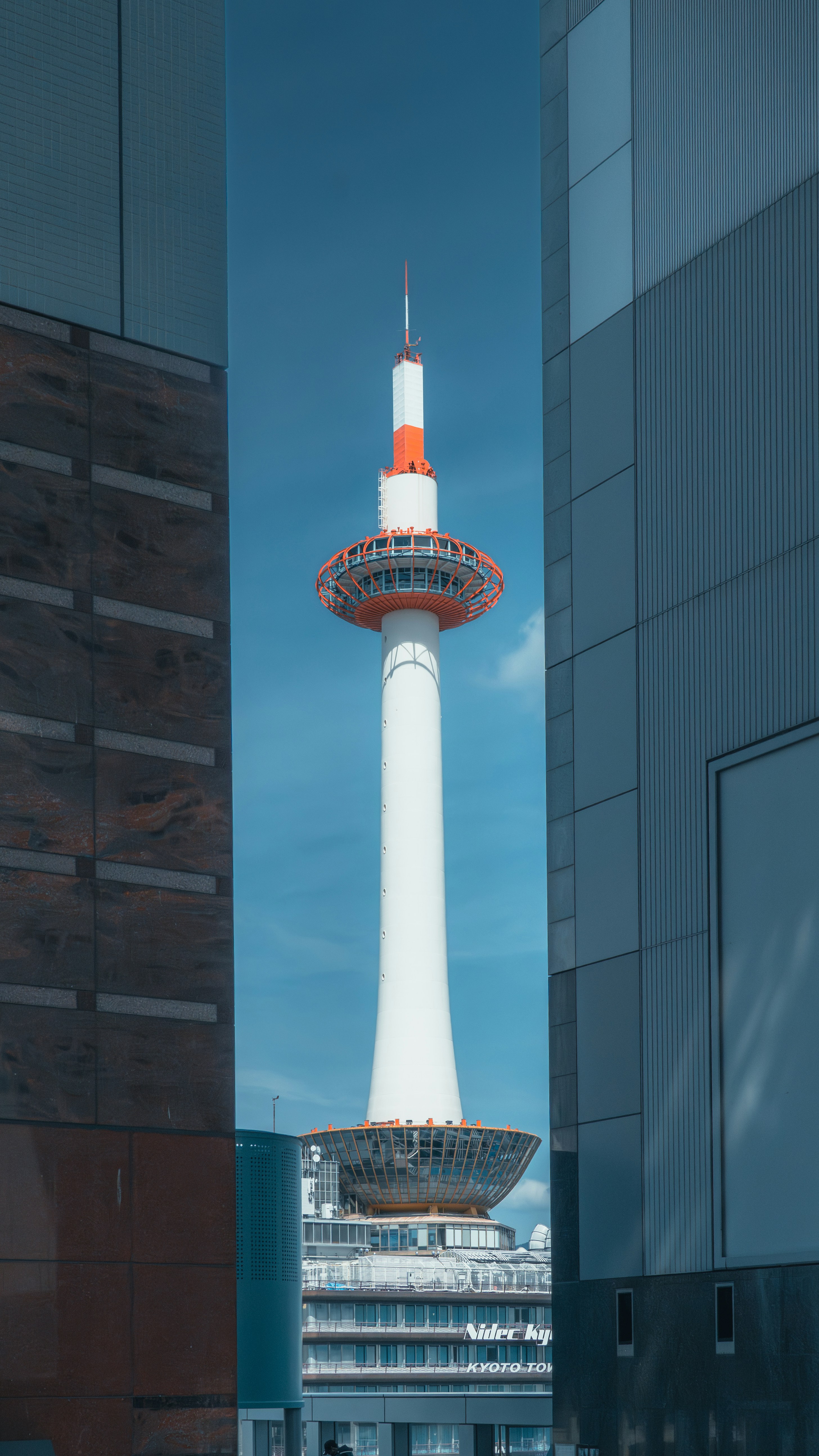 Kyoto tower is seen between two buildings.