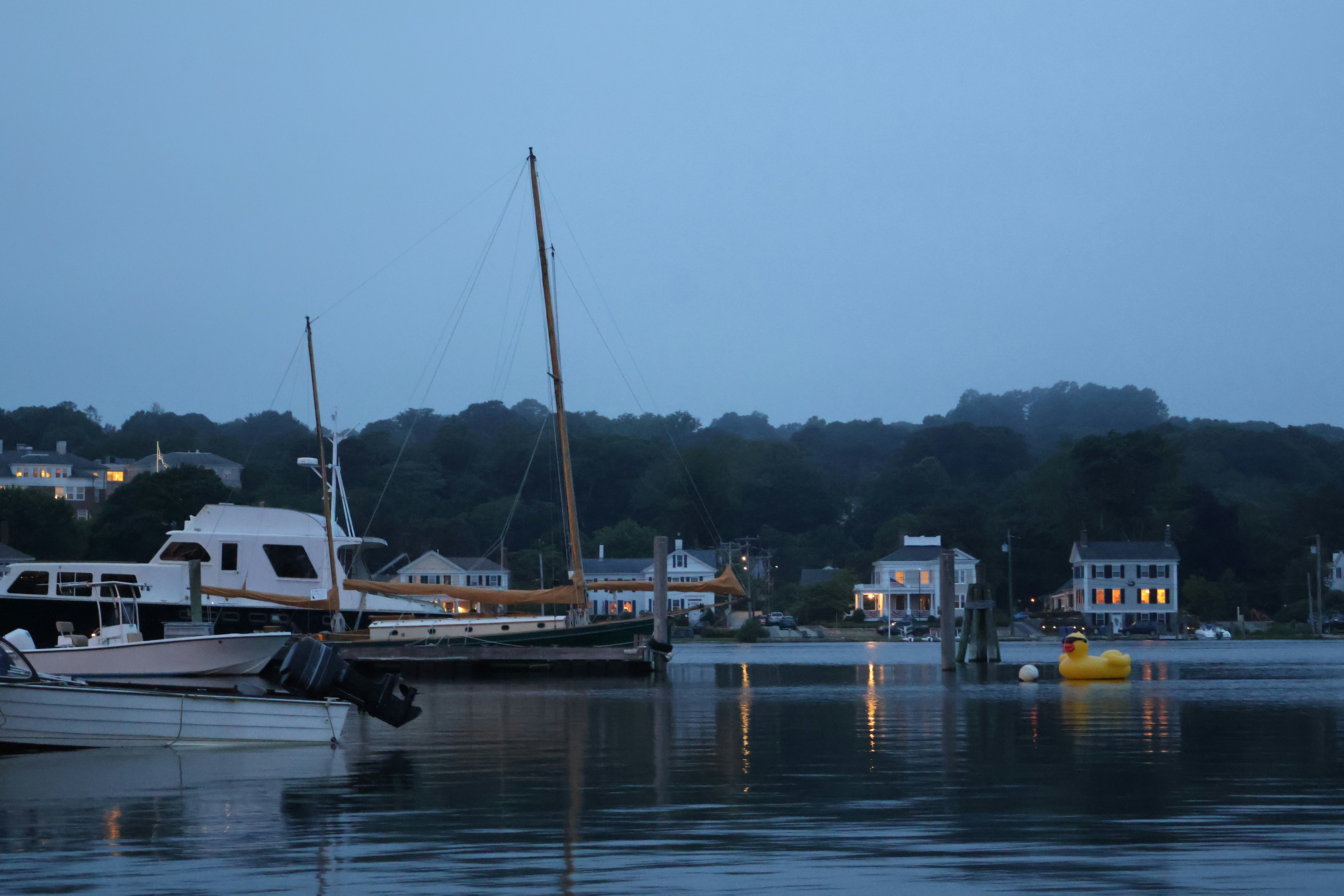 Boats in the harbor at dusk, by the shore.