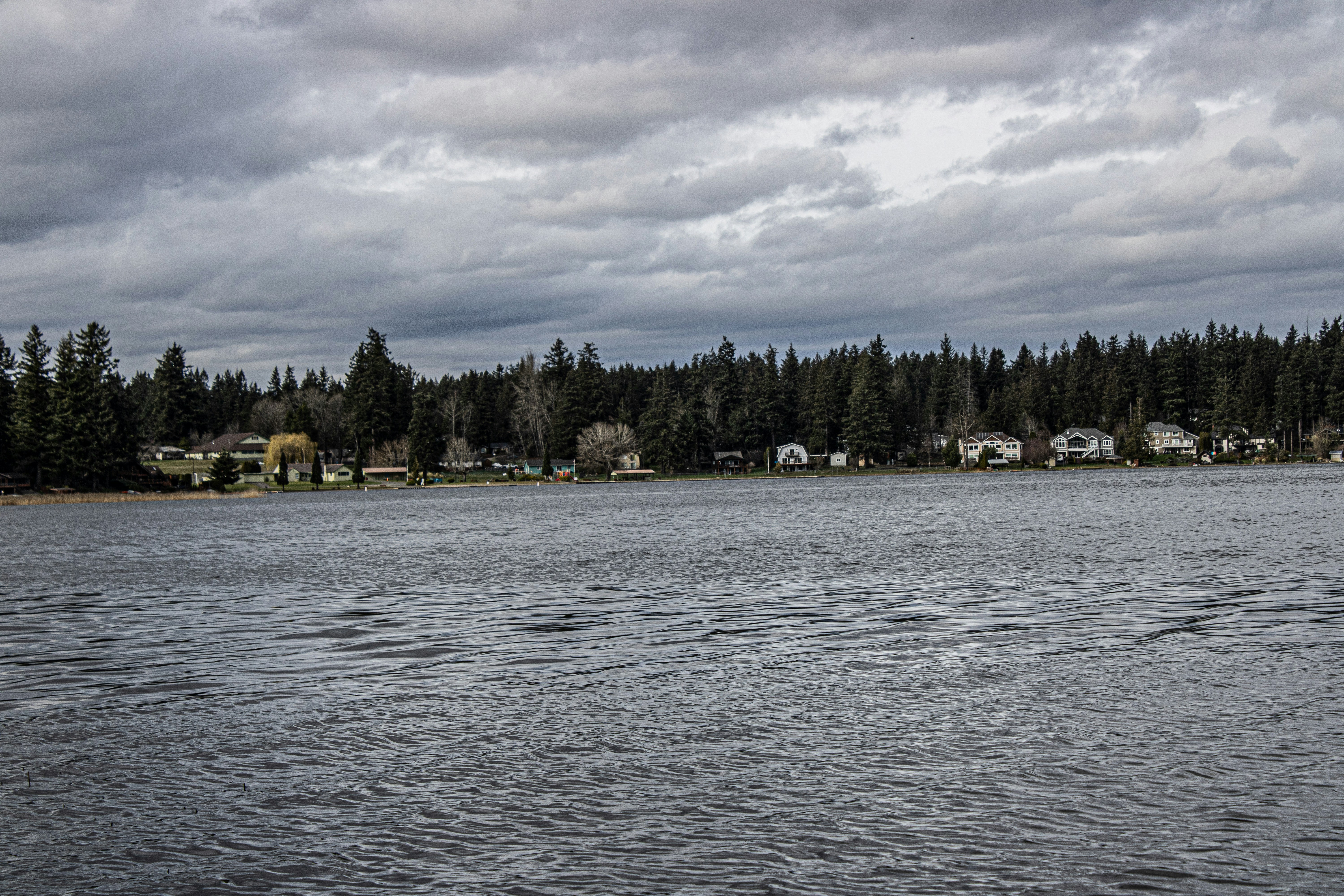 A lakeside view under a cloudy sky.