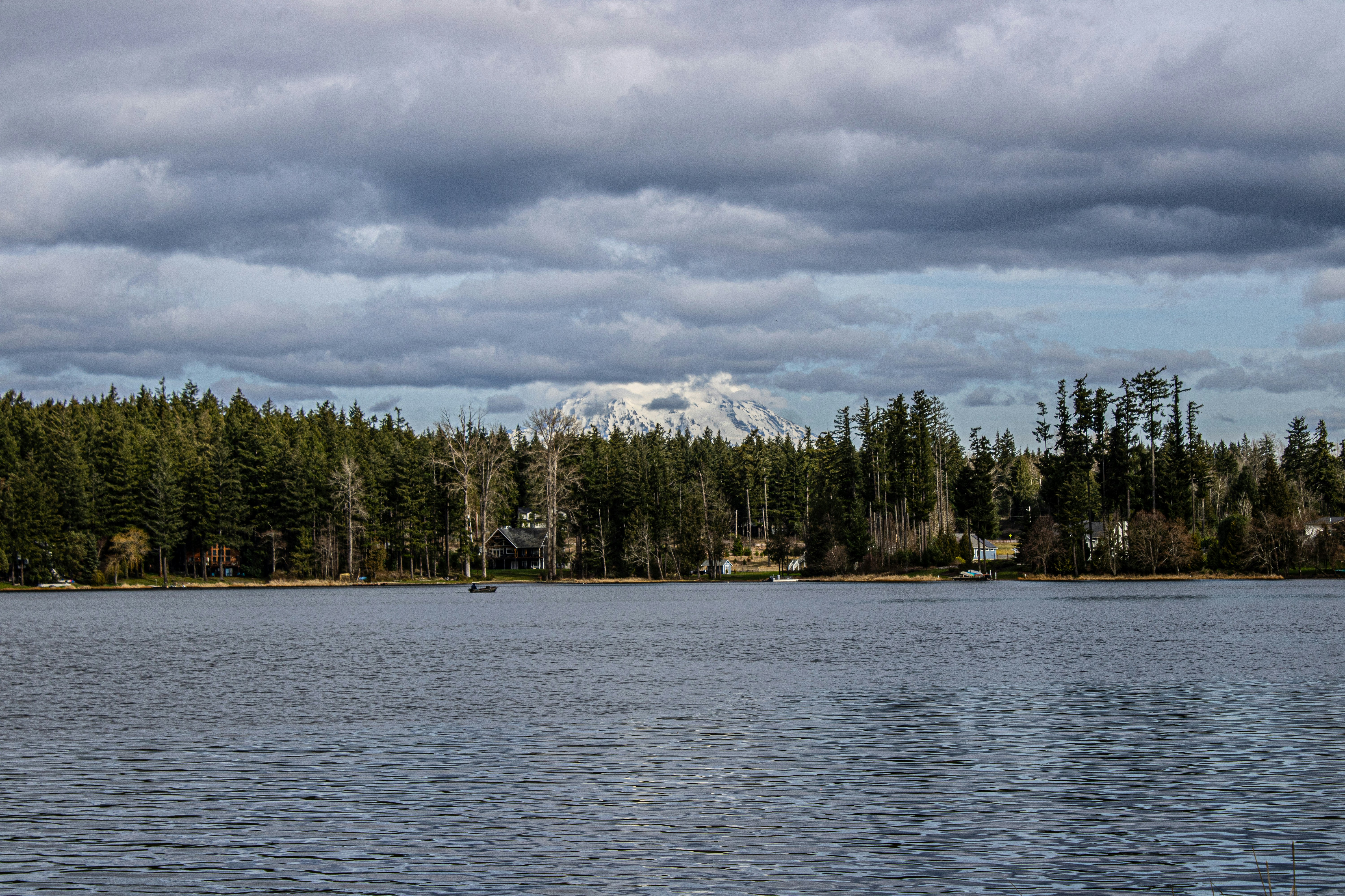 A lake reflects the trees and distant mountain.