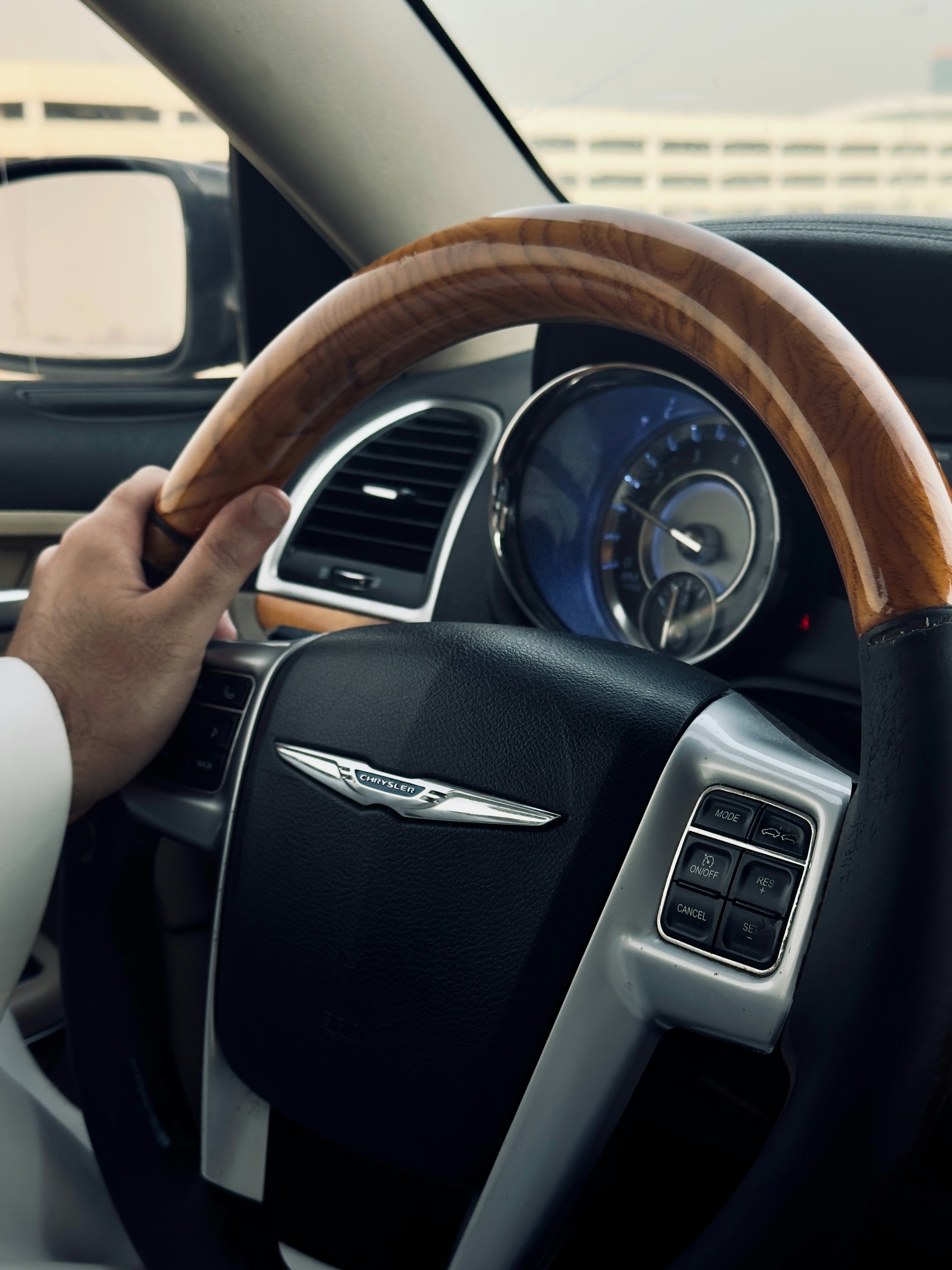 A hand grips the steering wheel of a car.