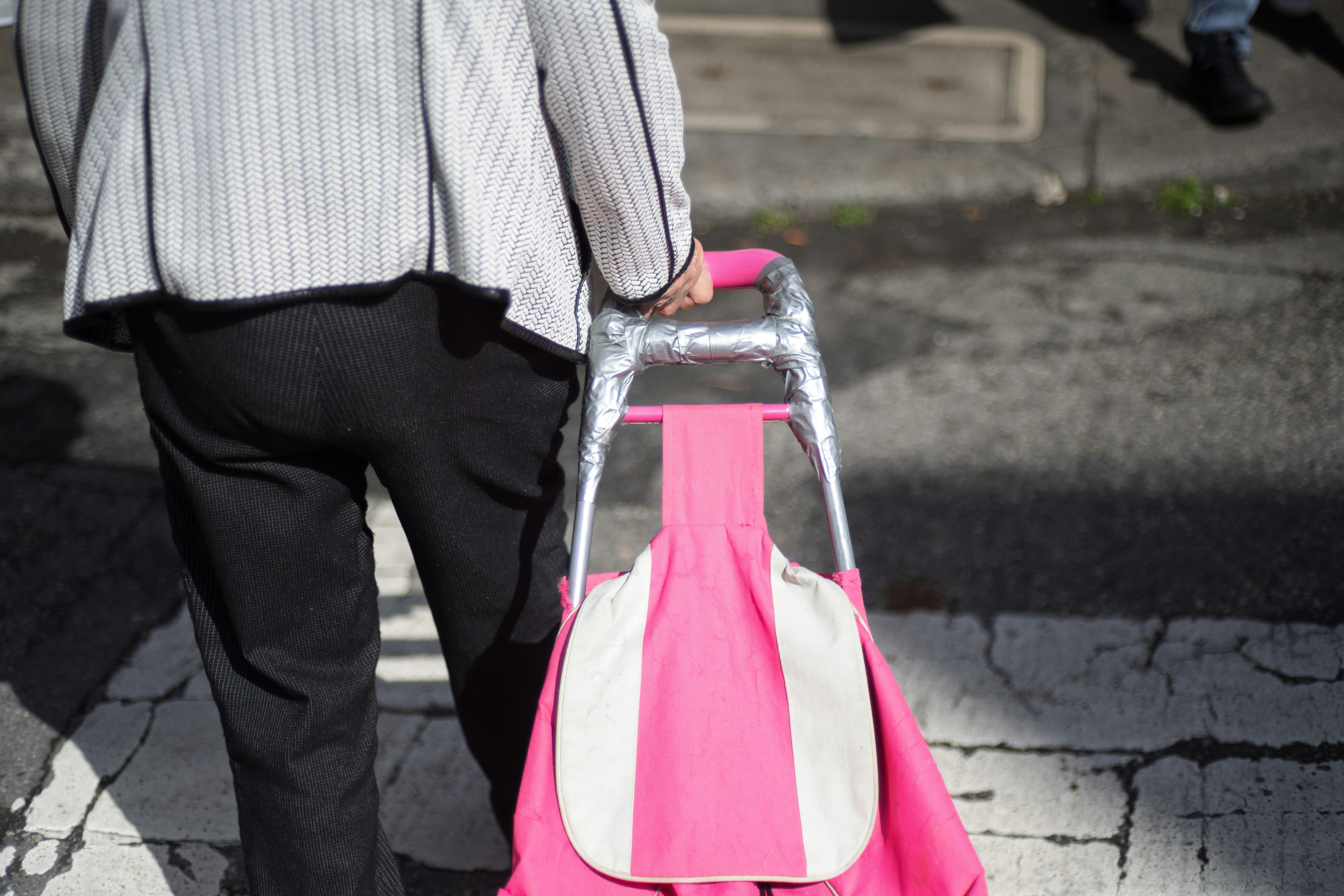 Person pulls a pink shopping cart.