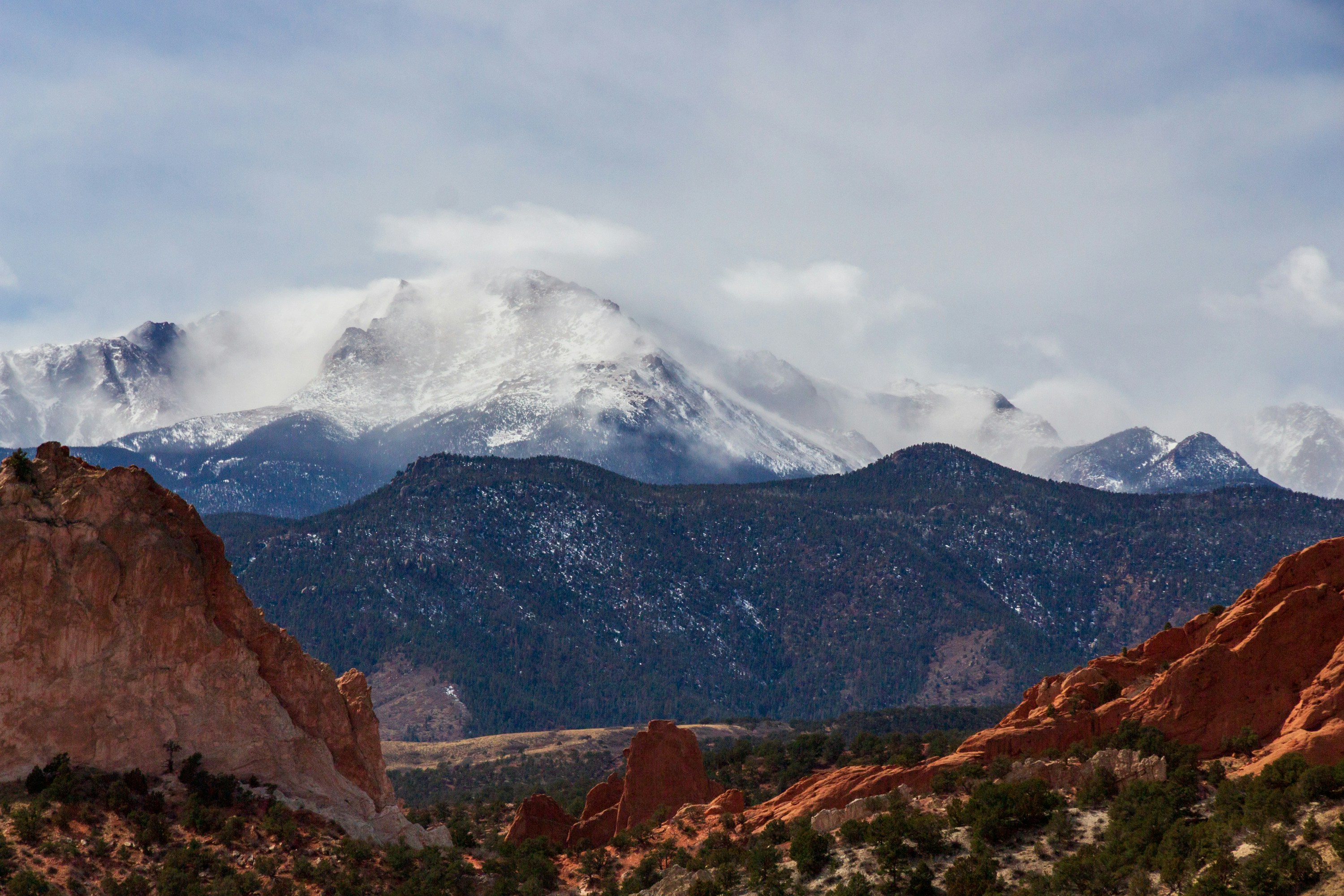 Snowy mountains rise over red rock formations.