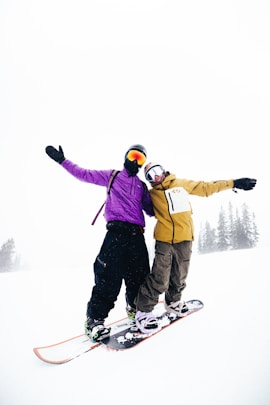 Two snowboarders celebrate on a snowy mountain.