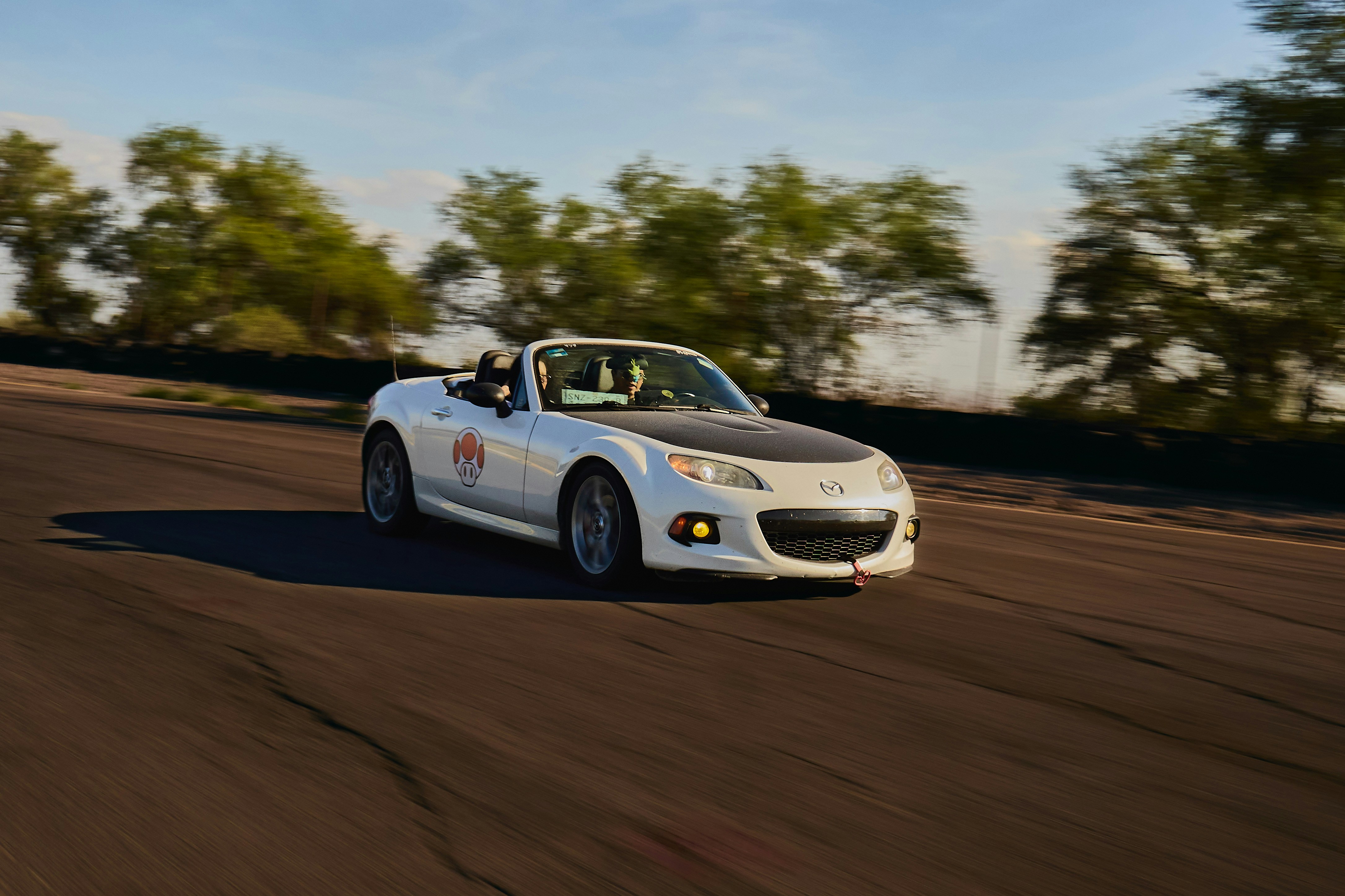 A white sports car drives along the track.