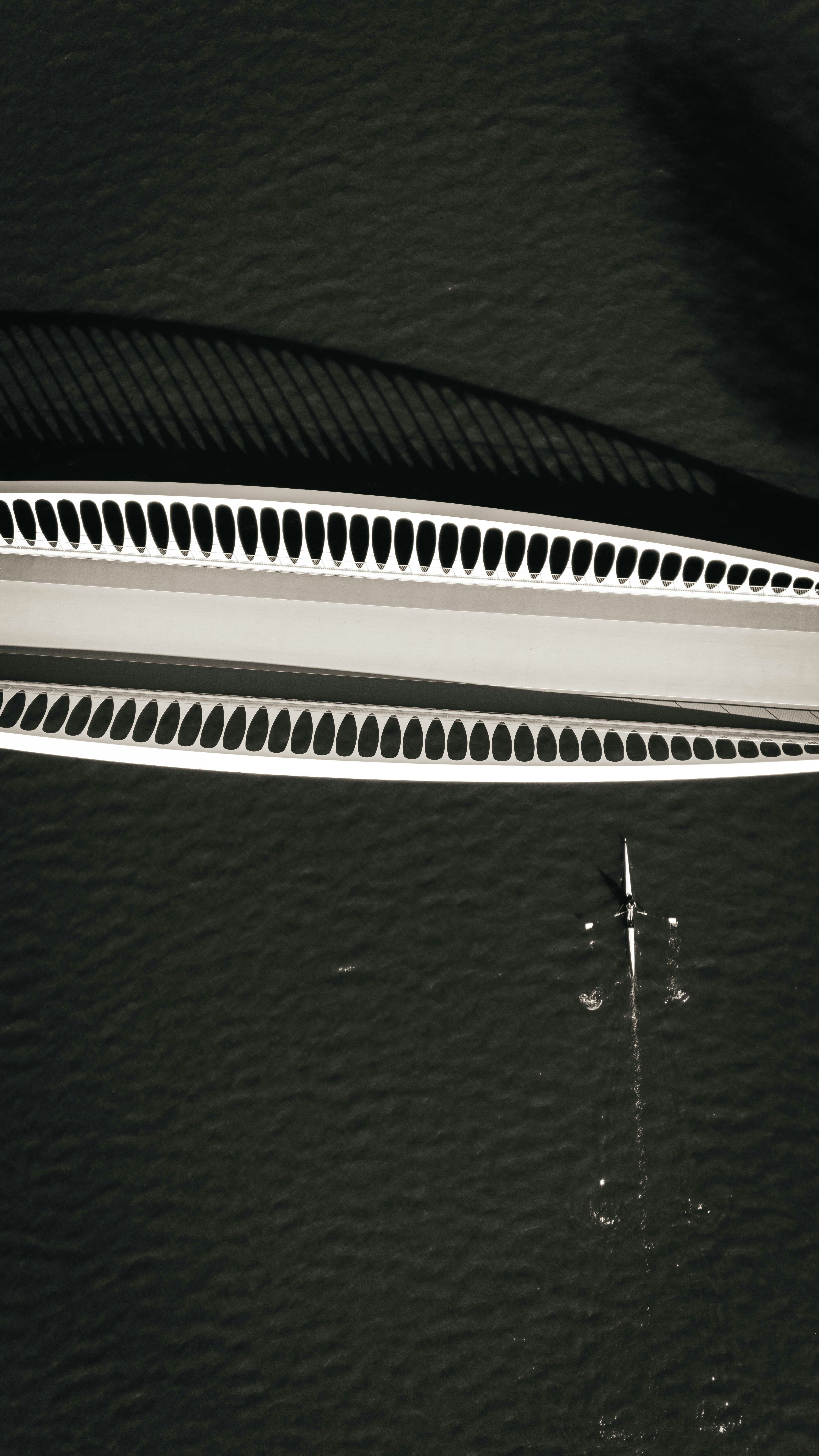 A bridge casts a shadow over a boat.