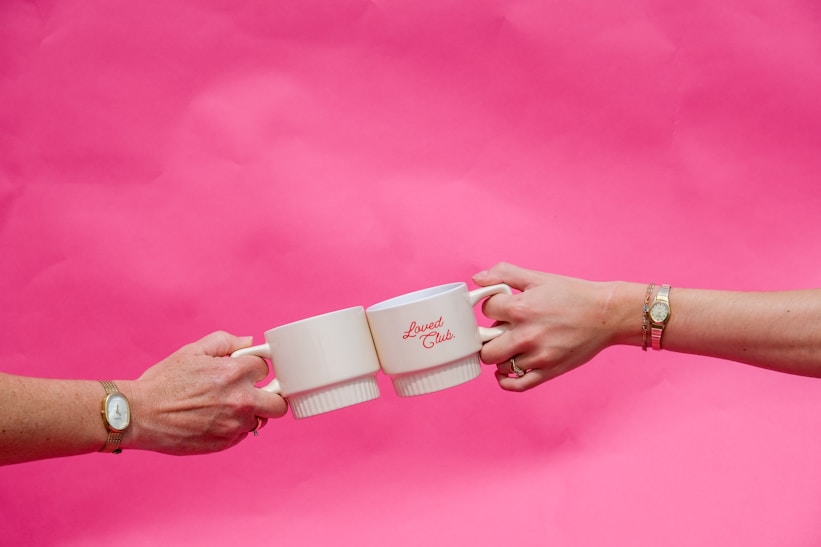 Hands clink coffee mugs in celebration.