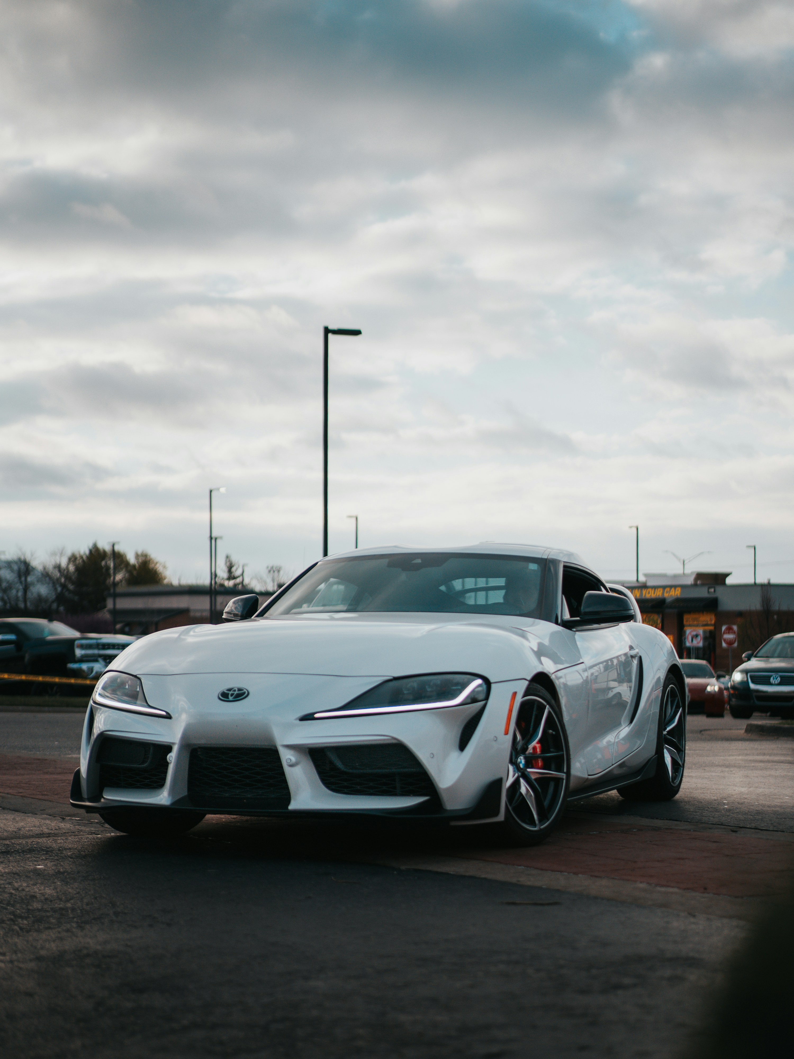 A white sports car is parked in a parking lot.