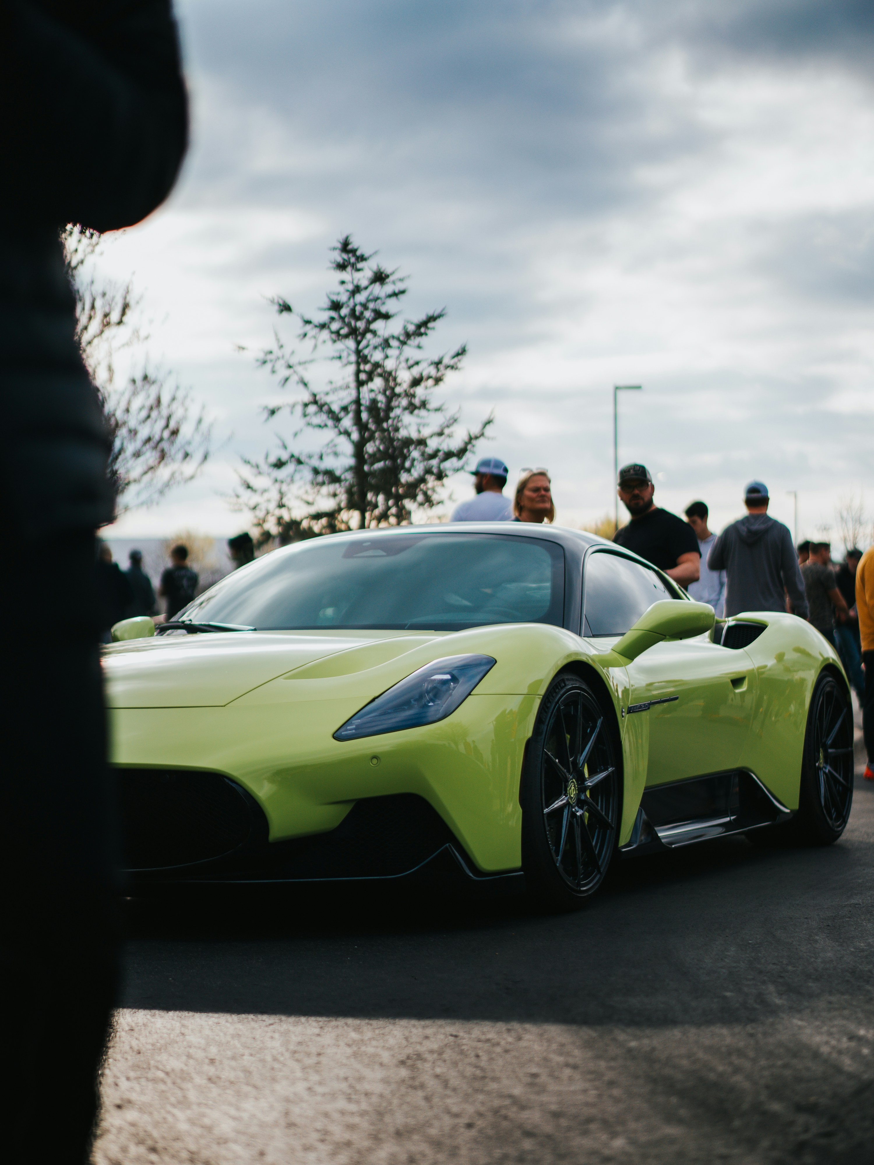 A bright green sports car is surrounded by people.