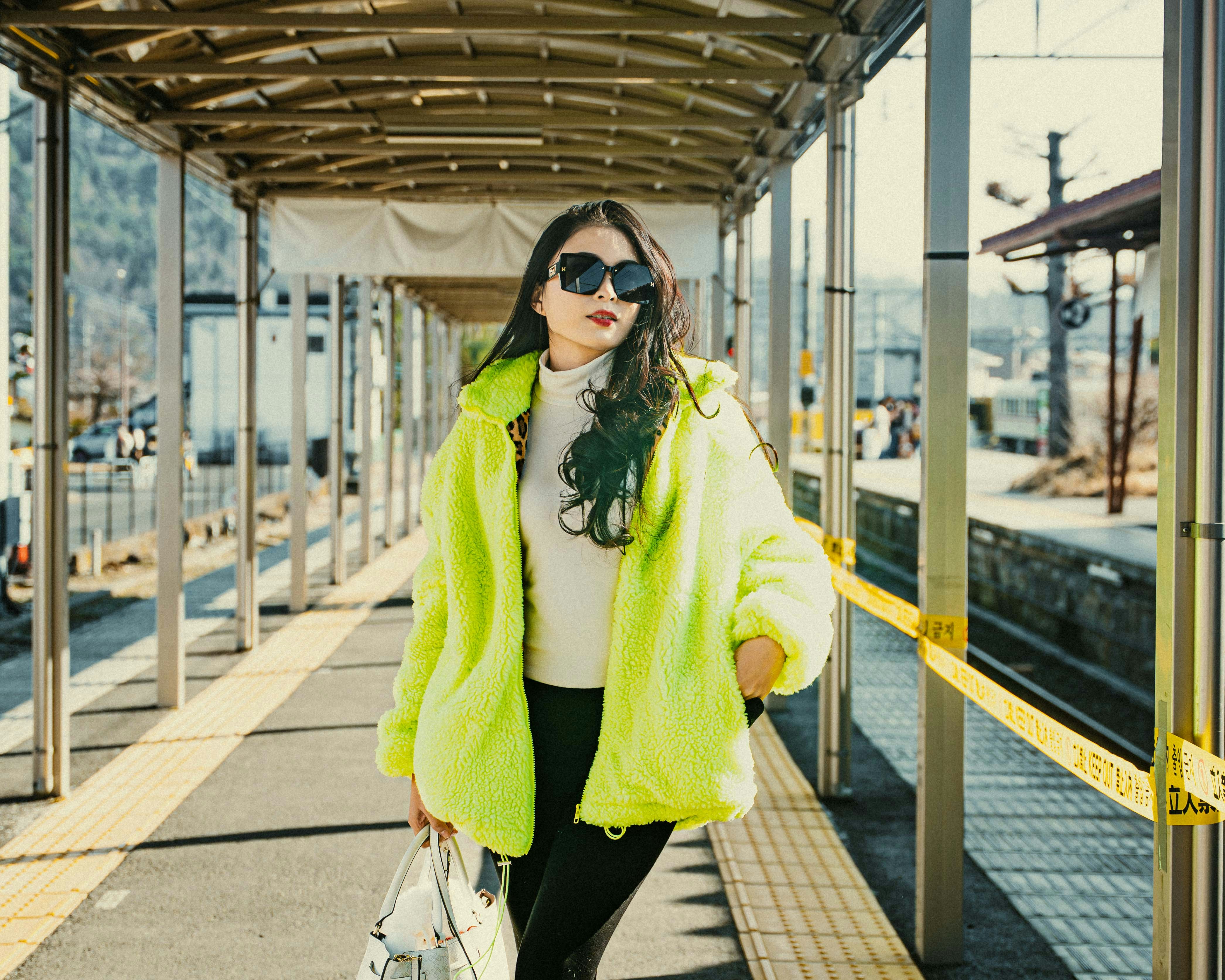 Woman in a neon jacket poses on a platform.