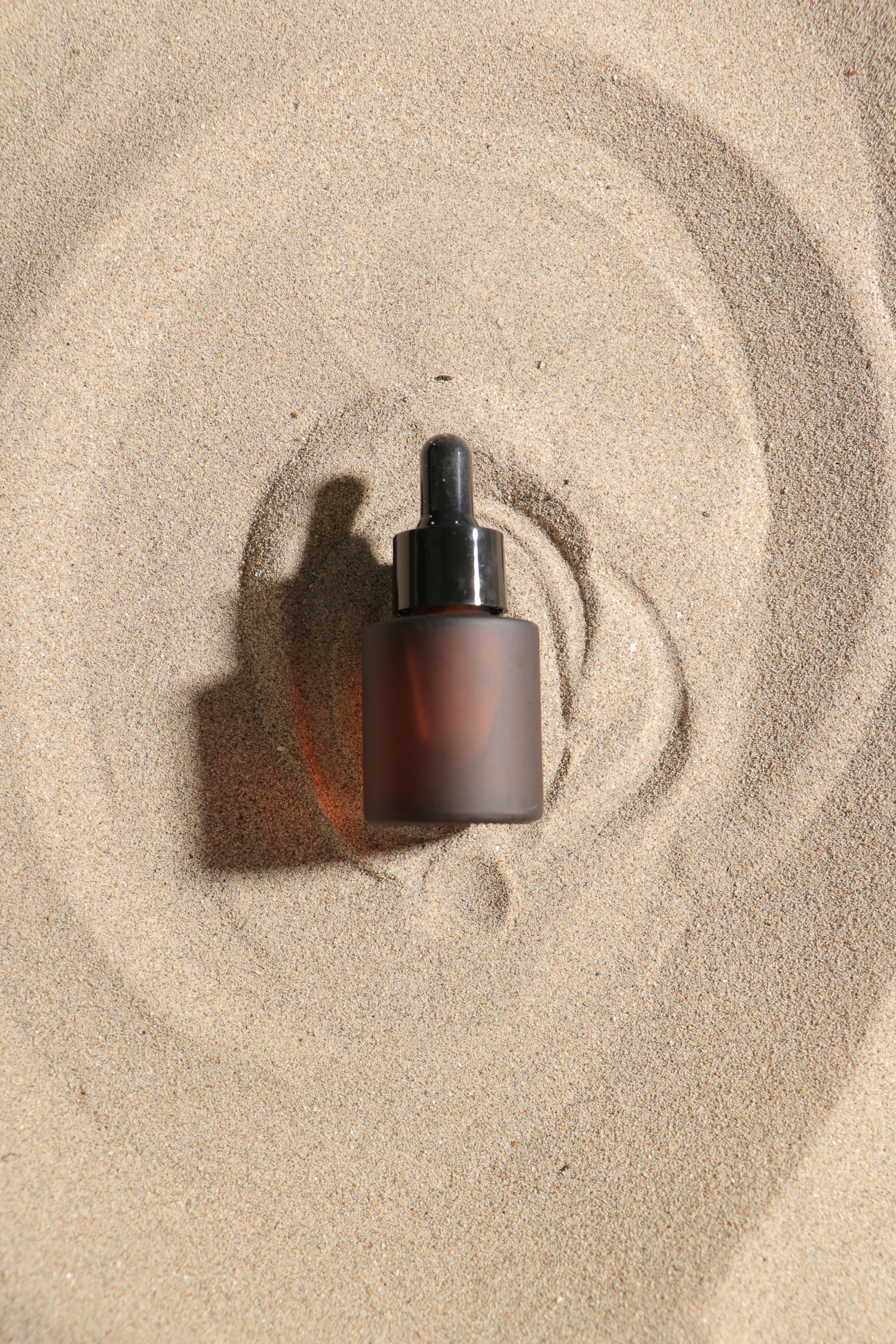 Squalane 100% Oil, in stock — an amber frosted dropper bottle resting in raked sand