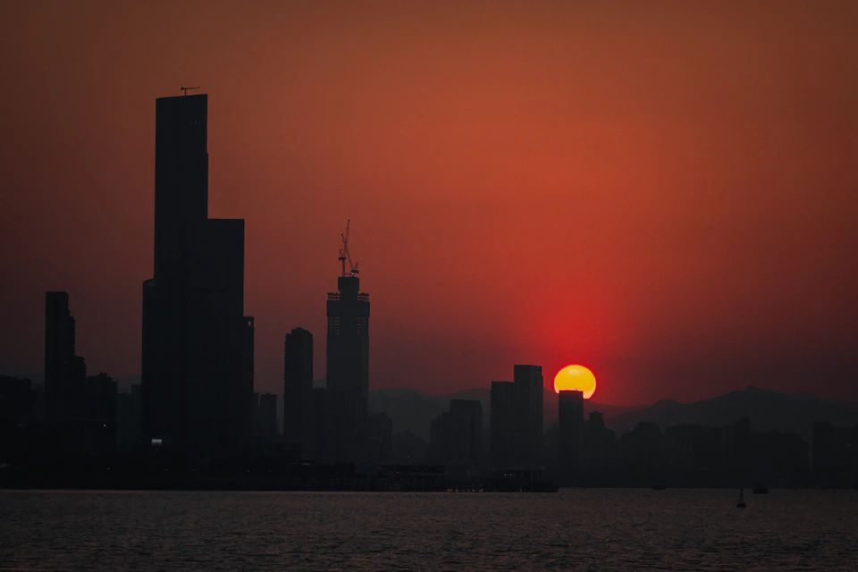 City skyline at sunset with warm glow and vibrant orange-red sky behind tall buildings