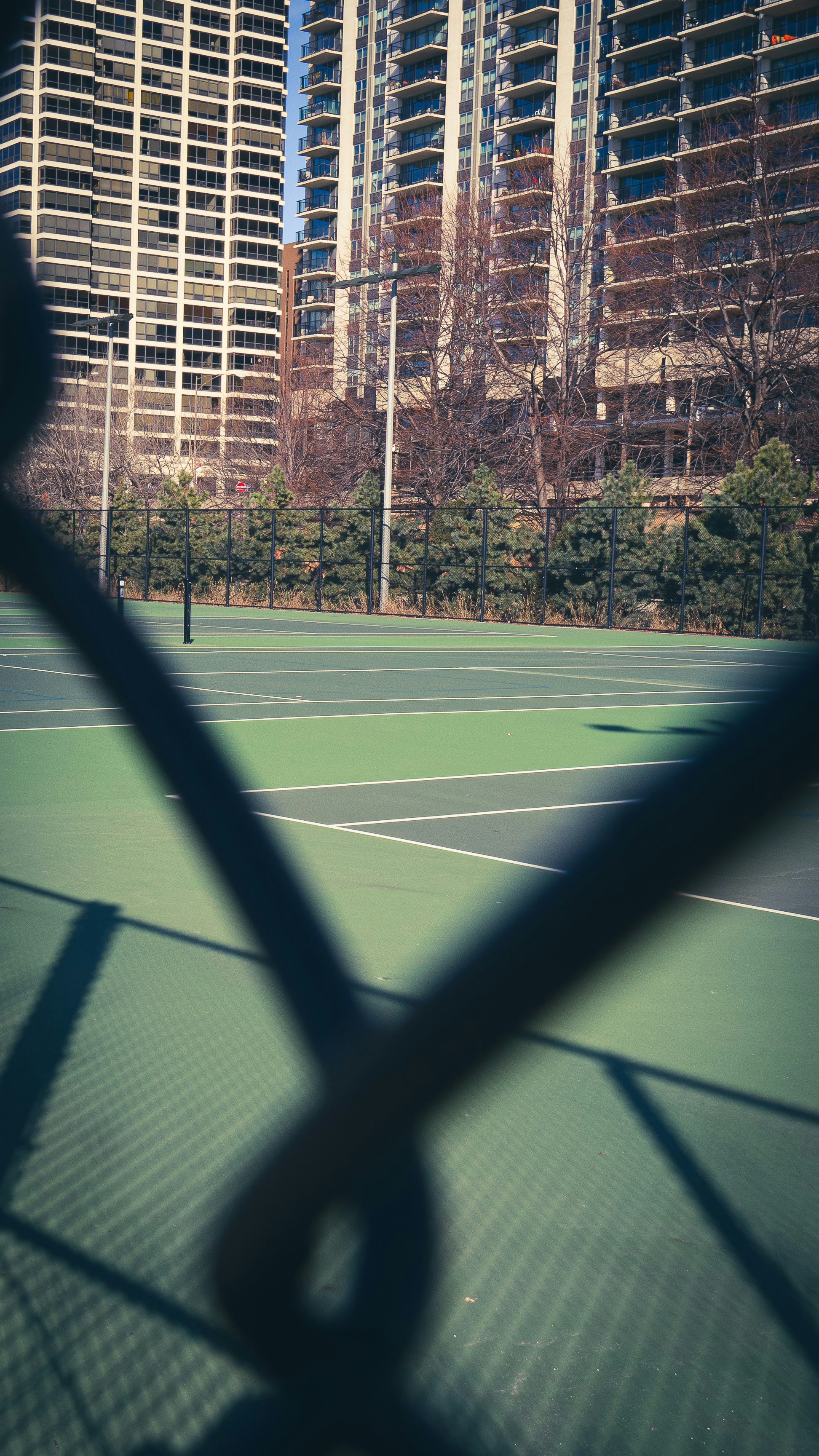 A tennis court is seen through a chain link fence.
