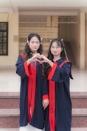 Two graduates form a heart with their hands.