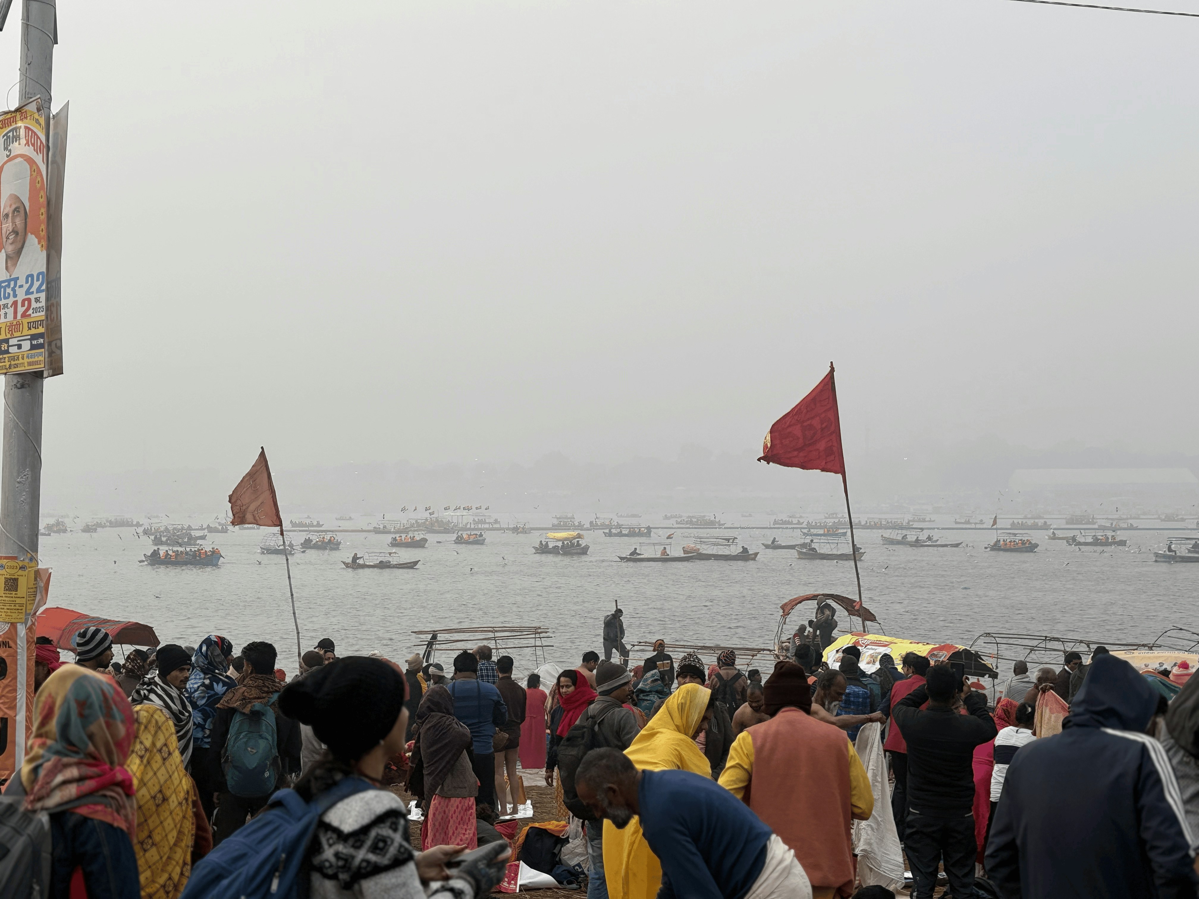 People gather near a river, with boats on it.