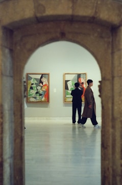 People observe paintings in an art gallery.