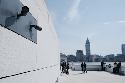 Surveillance cameras on a modern building overlook the city.