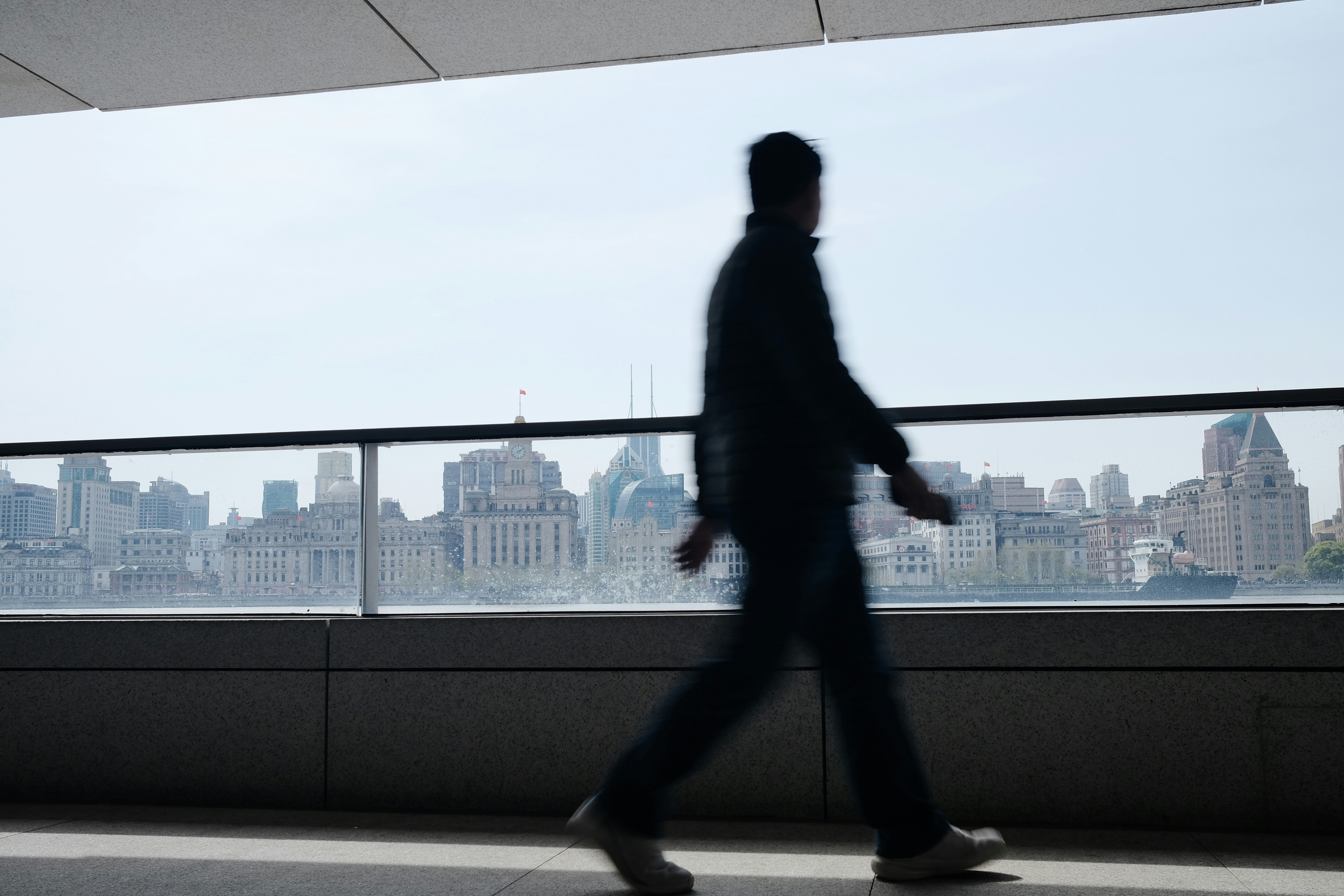 A person walks with a city skyline in background.