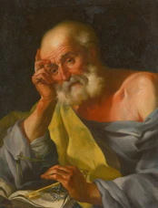An old man with a beard reading a book.