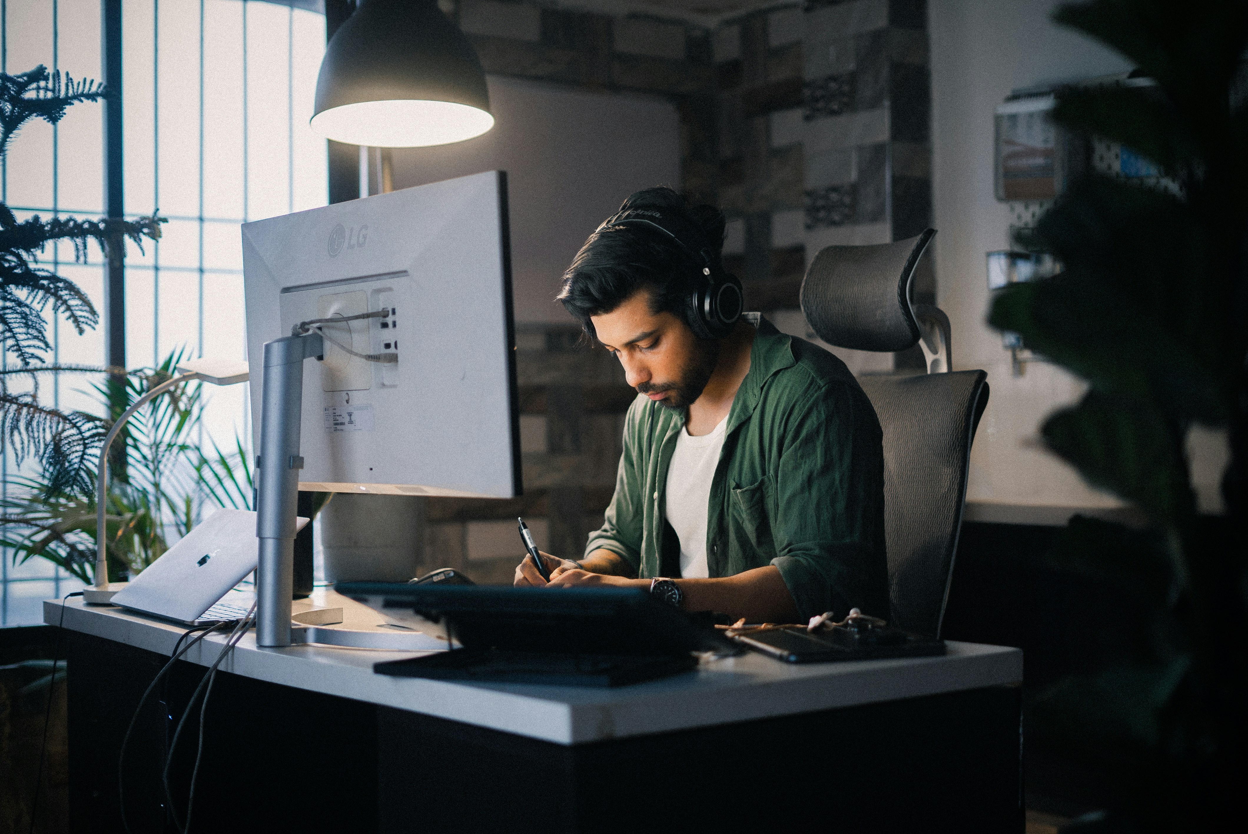 Um homem trabalha atentamente em uma mesa de computador.
