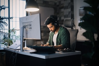 A man works intently at a computer desk.