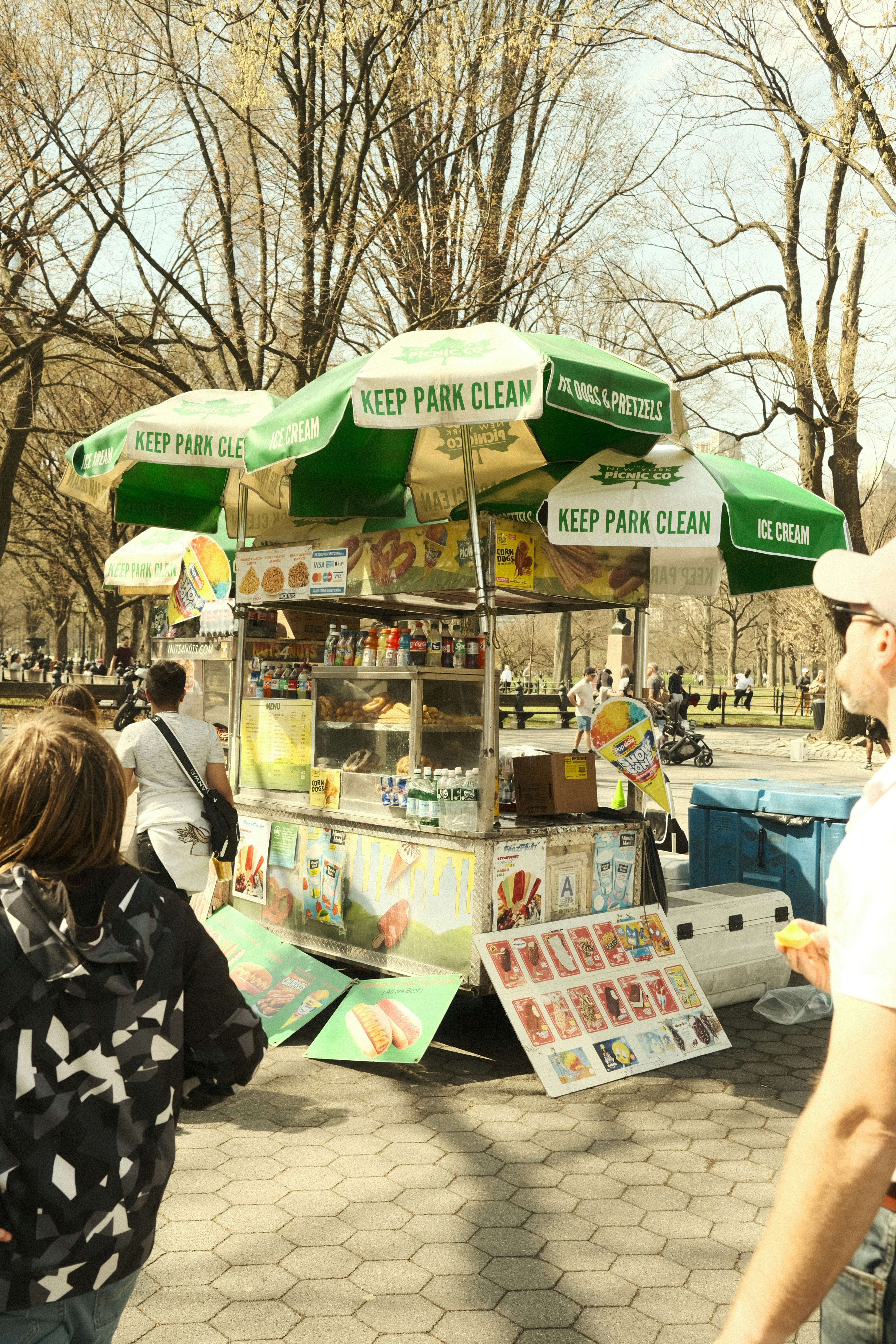 A hot dog cart sits in a park