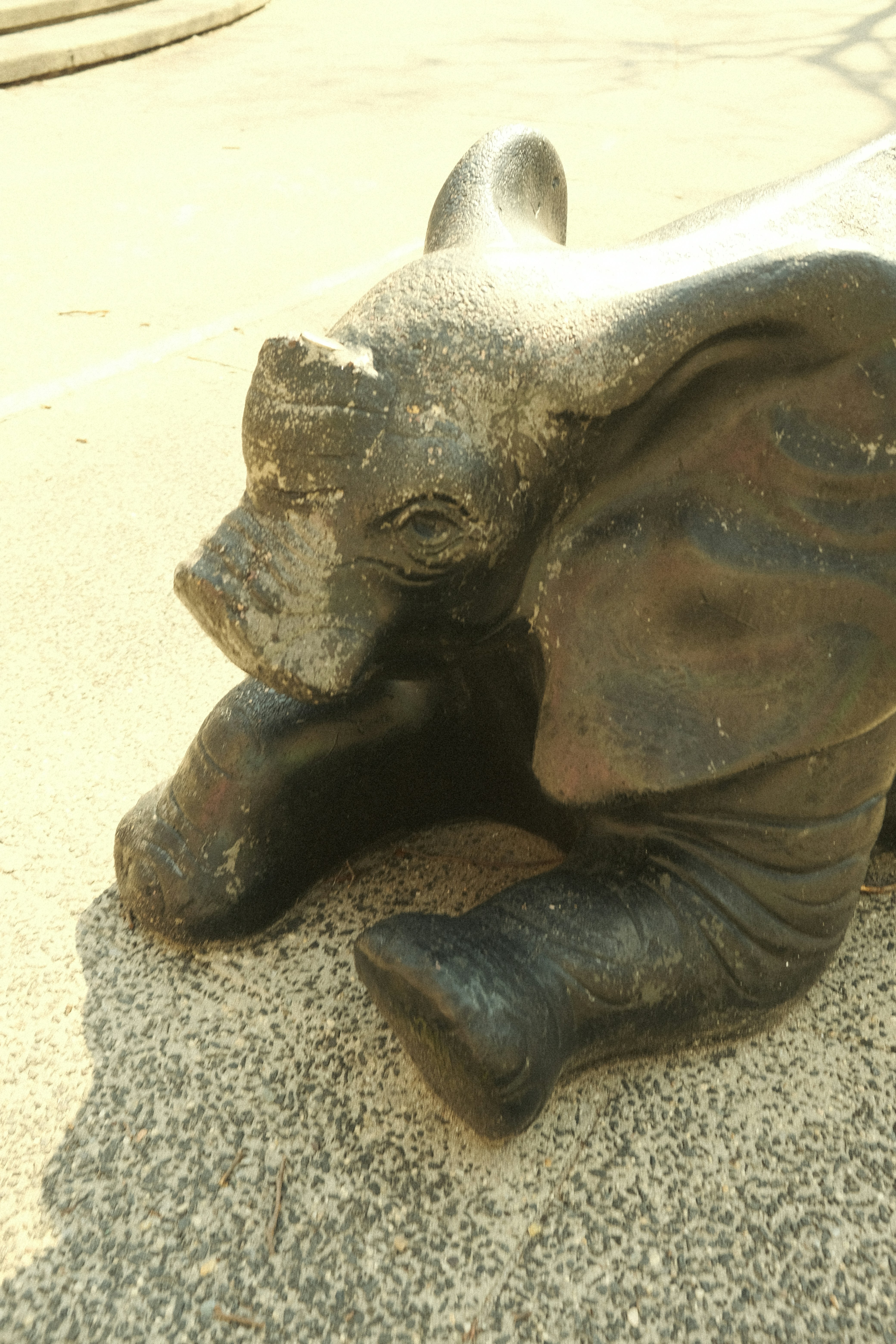 An elephant statue is lying on the ground.