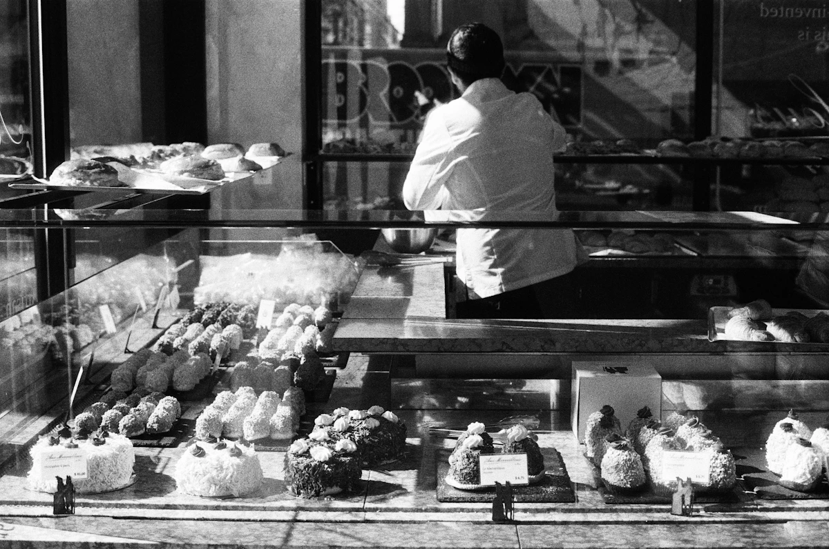 A bakery owner working behind a counter full of pastries