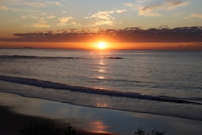 Sunrise over the calm ocean with reflections.