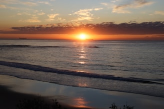 Sunrise over the calm ocean with reflections.