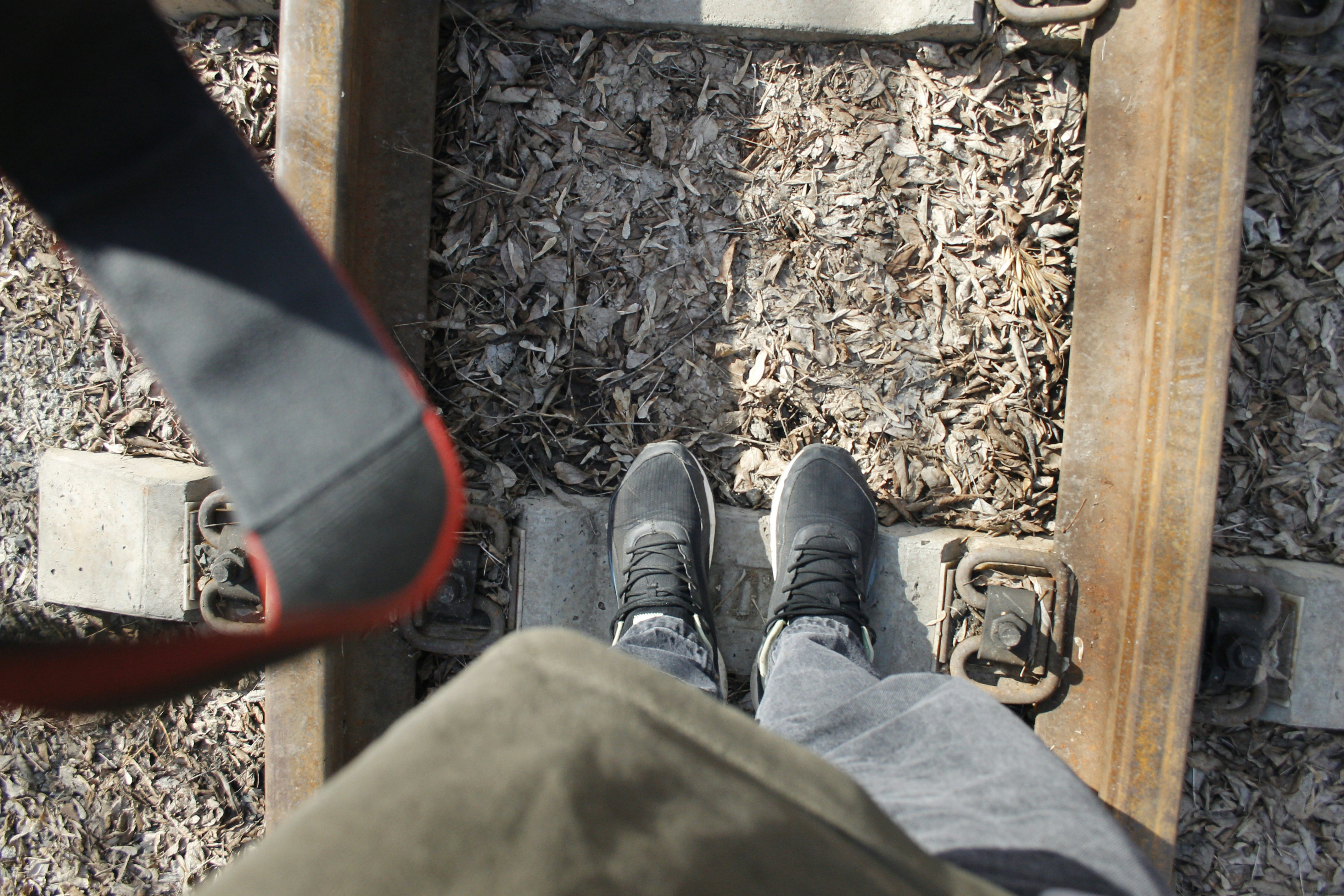 Shoes stand on railroad tracks.