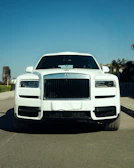 A white rolls-royce suv parked in bright sunlight.