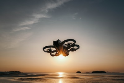 A drone flies against a sunset's backdrop.