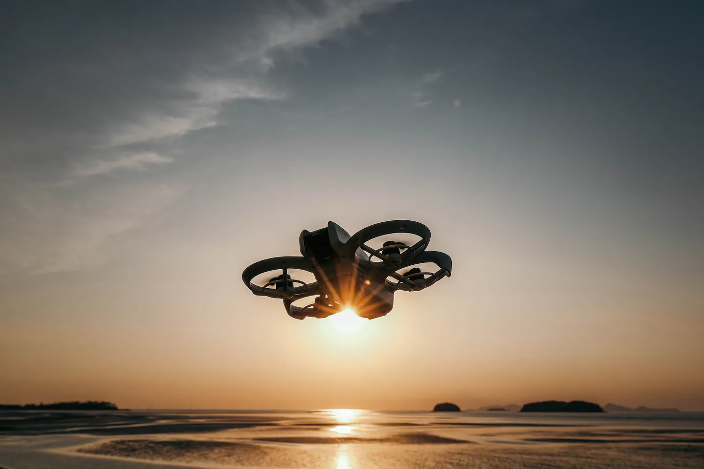 A drone silhouetted against a sunset sky