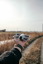 A person is holding a small drone outdoors.