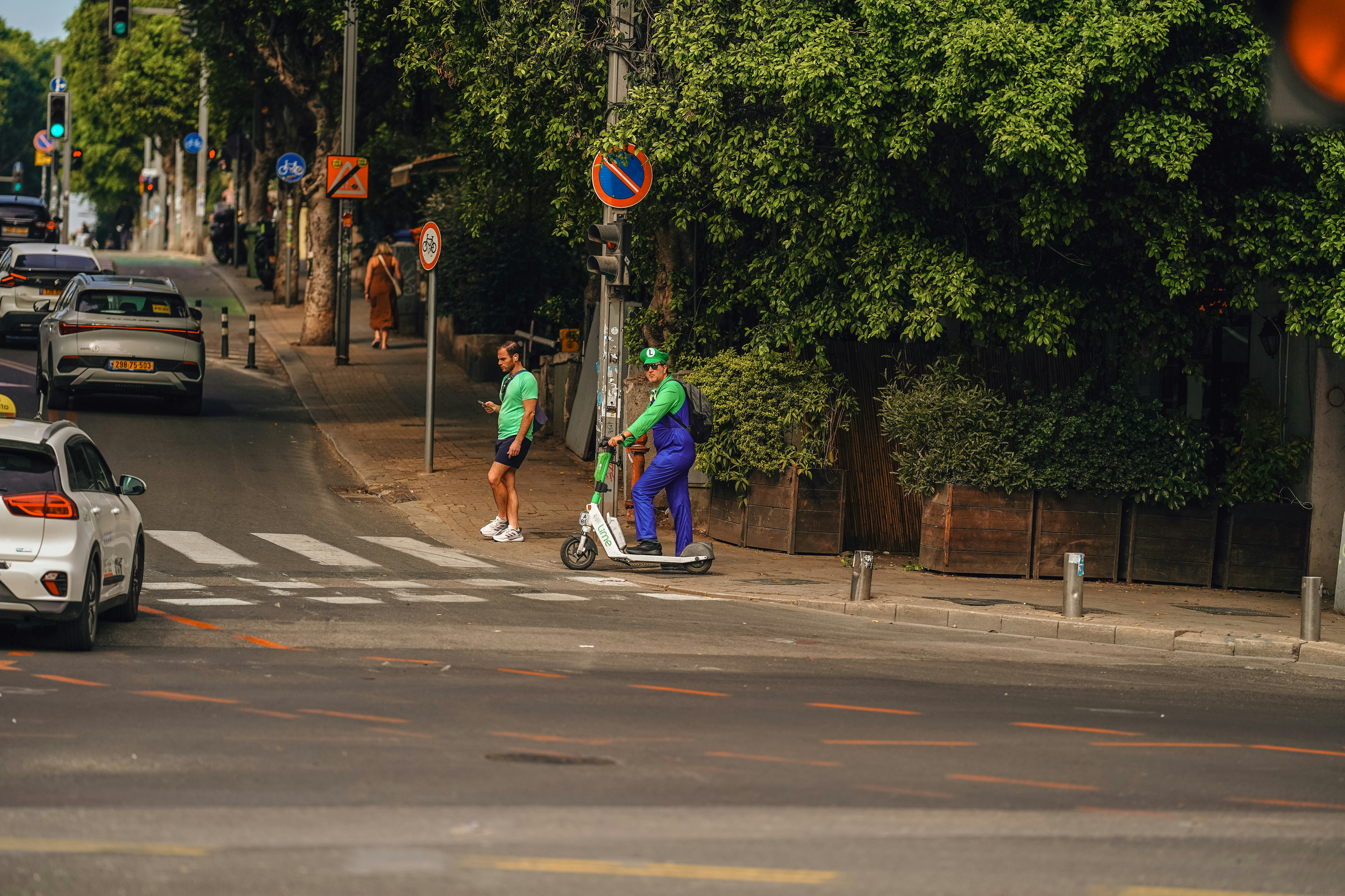 A person on a scooter waits at a crosswalk.