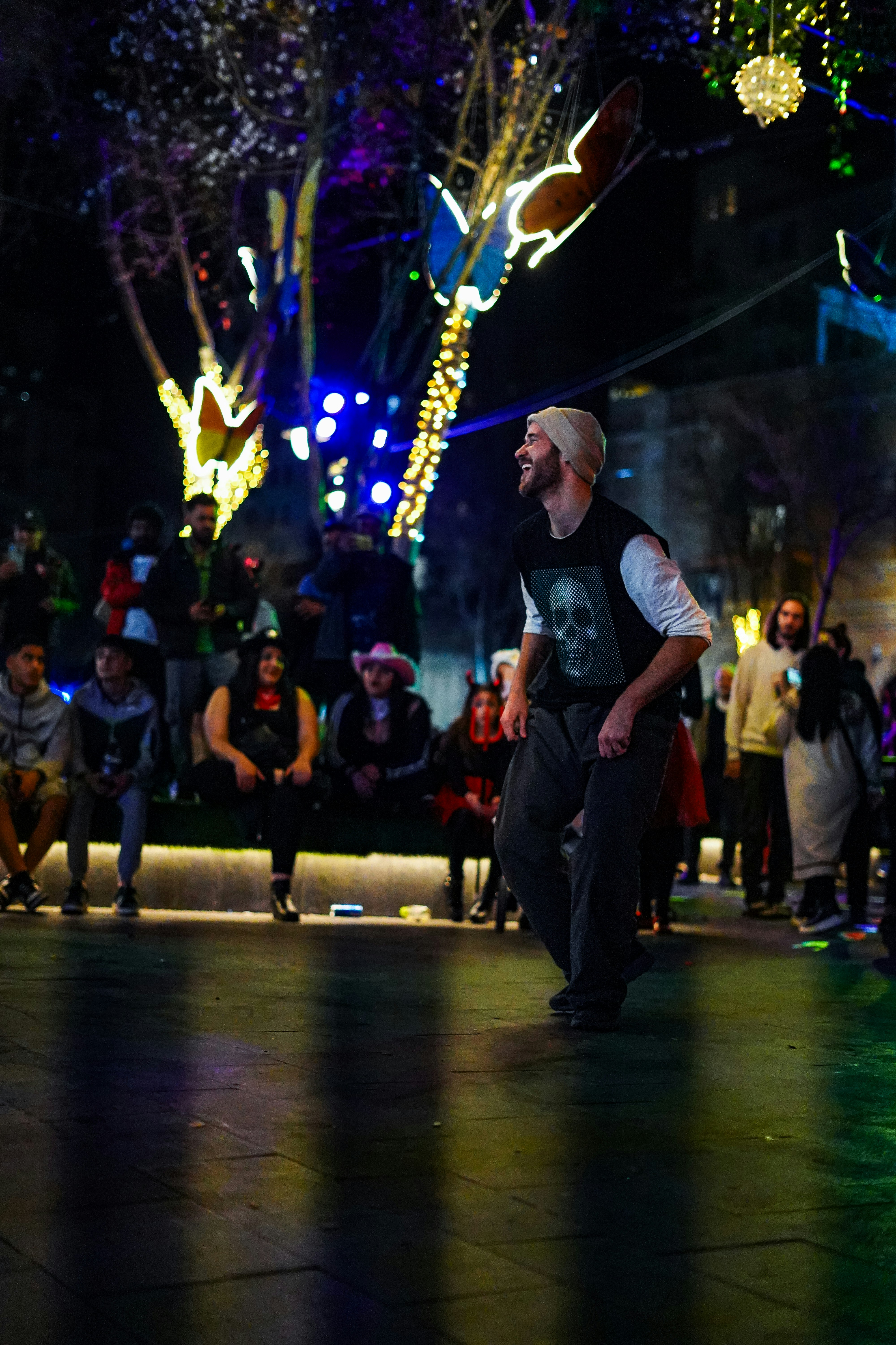 A man dances under festive, nighttime lights.