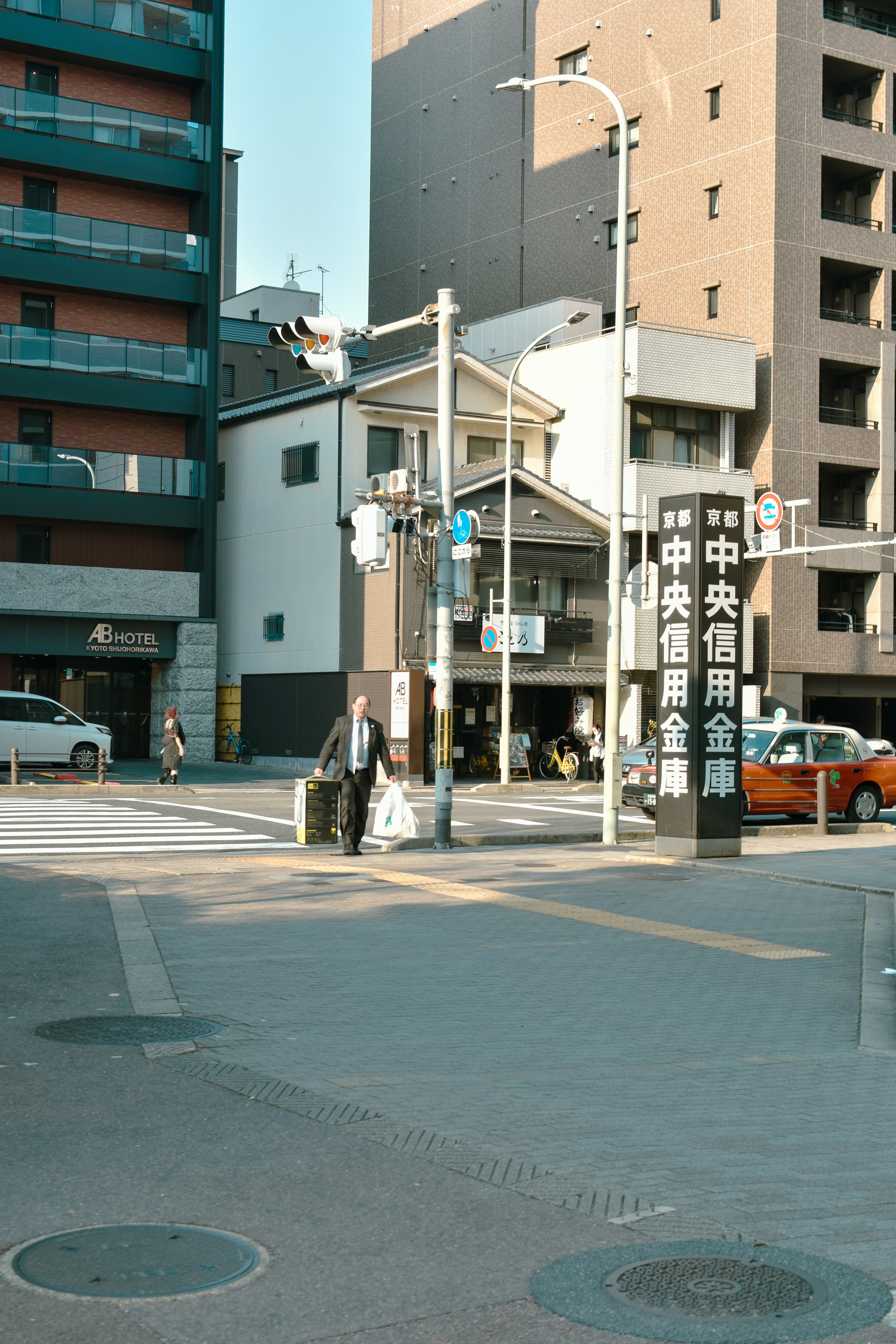 A businessman carries luggage across a city street.